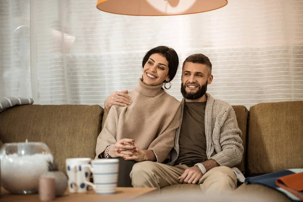 Casal bonito de cabelos escuros sentado extremamente perto um do outro enquanto assiste TV — Fotografia de Stock