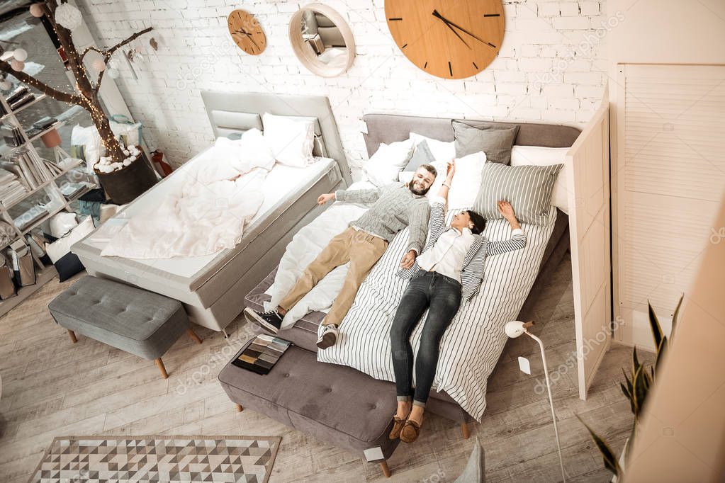 Interested couple examining quality of mattress for their future life