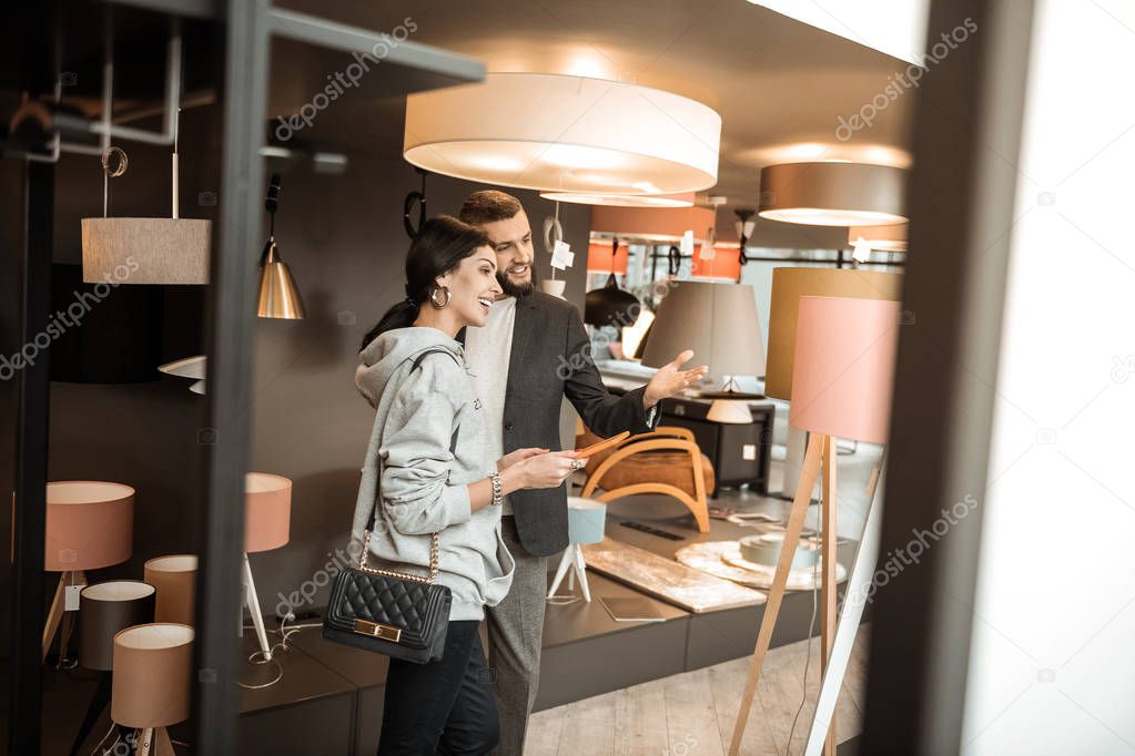Laughing lady looking on lamp while man pointing on it