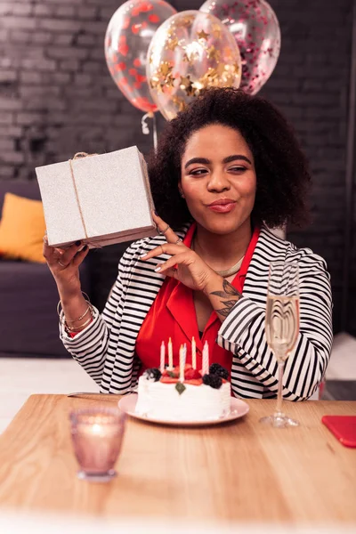 Positive joyful woman shaking her birthday present