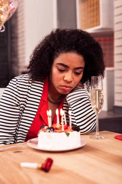 Cheerless unhappy woman having a sad birthday celebration