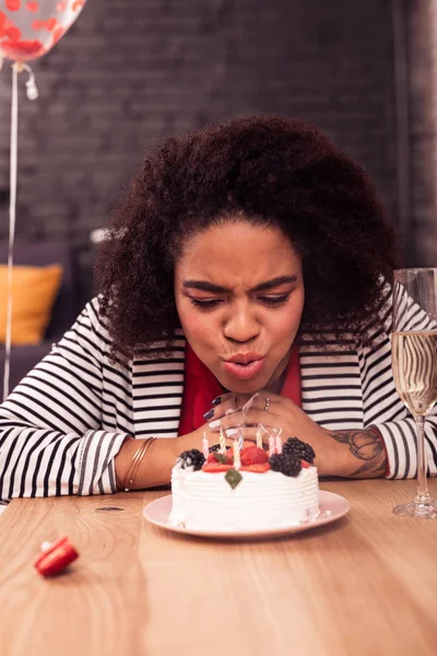 Mujer alegre agradable soplando velas en el pastel — Foto de Stock