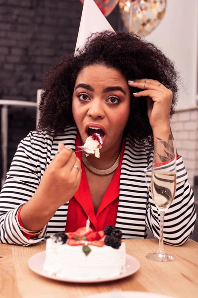 Cheerless giovane donna mettendo torta in bocca — Foto Stock