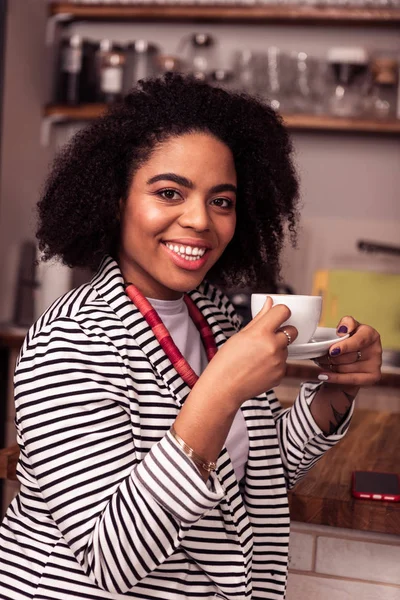 Happy delighted woman enjoying her tasty cappuccino