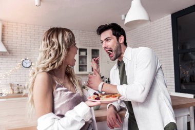 Koyu renk saçlı sakallı adam beyaz bir gömlek ve eşi kahvaltıda eğleniyor