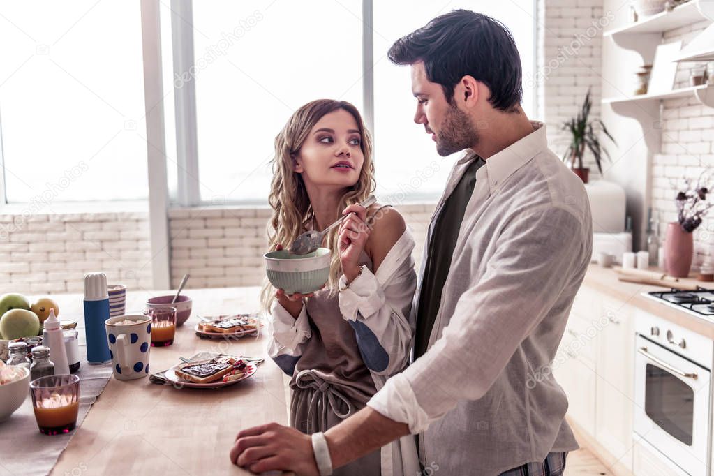 Pretty long-haired young woman in a white shirt and her husband enjoying breakfast