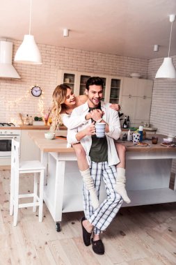 Koyu renk saçlı sakallı genç adam damalı pantolon eşi ile iyi vakit geçiriyor