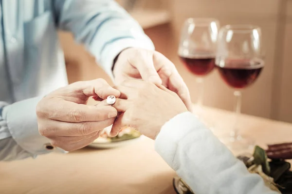 Close up de mãos masculinas colocando anel de noivado no dedo — Fotografia de Stock