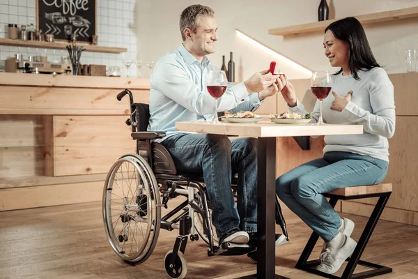 Smiling man in wheelchair making a surprise to woman