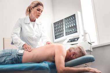 Profesyonel fizyoterapist yaşlı adam için masaj yapıyor