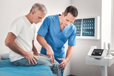 Esmer doktor diz inceleyerek mavi üniforma