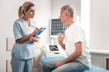 Mavi gözlü hemşire hasta dikkatle dinlerken Bakımı