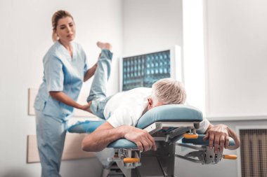 İnceleyerek onun bacakları olan gri saçlı yaşlı adam