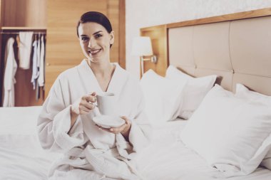 Şık ve bakımlı kadın yatakta otelde oturuyordu