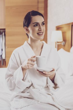 Konforlu yatağın üstüne oturan hoş Bayan