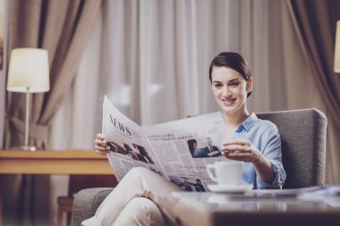 Haber duyuru. Çekici görünüm sahip ve gazete makalelerinde heyecanla okurken evde vakit hoş olumlu iş kadını