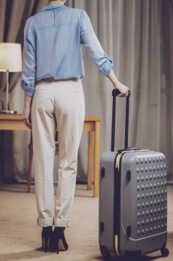 Bagaj. Kamera için onu geri dolapla ortasında duran ve bir bavul holding resmi elbiseli şık ve bakımlı güzel kadın