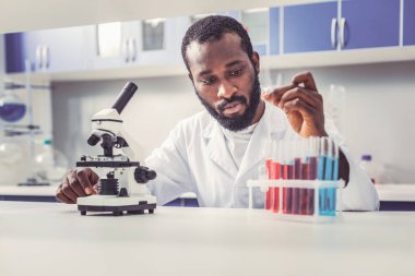 Sakallı genç biotechnologist cam tüpleri ile çalışma