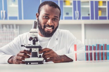 Mikroskop oturan kimyager olarak çalışan siyah gözlü adam