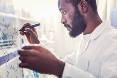 Ciddi görünümlü genç kimyager kimyasal formül yazma