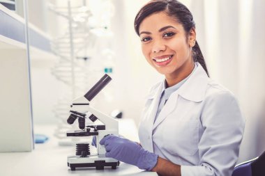 Beyaz mikroskop oturan üniforma giyen genç kimyager