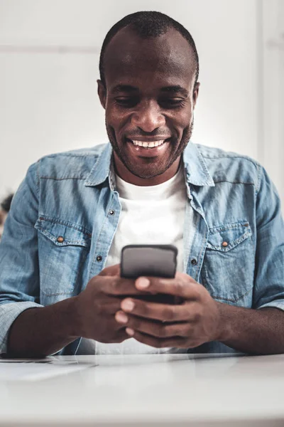 Веселый счастливый человек смотрит на экран смартфона — стоковое фото