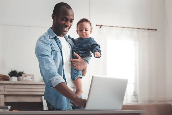 Alegre hombre agradable mirando la pantalla del ordenador portátil — Foto de Stock