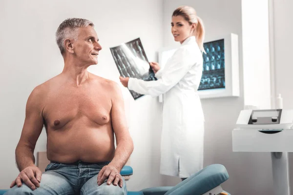 Uomo dai capelli grigi guardando giovane infermiera dai capelli biondi — Foto Stock