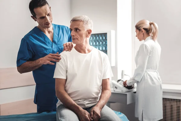 Aggódik az ember ül orvosi szobában pótágy fehér inget visel — Stock Fotó