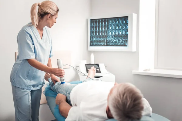 Blonde-haired slimme medisch assistent onderzoek van de knie — Stockfoto