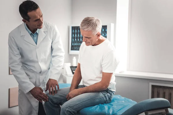 Retired man sitting and explaining his pain in knee — Stock Photo, Image