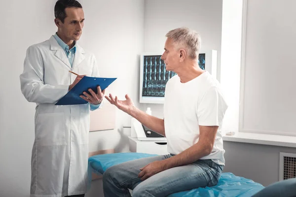 Grey-haired man asking the doctor about further checkups — Stock Photo, Image