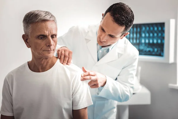 Осторожный темноволосый врач осматривает плечо — стоковое фото