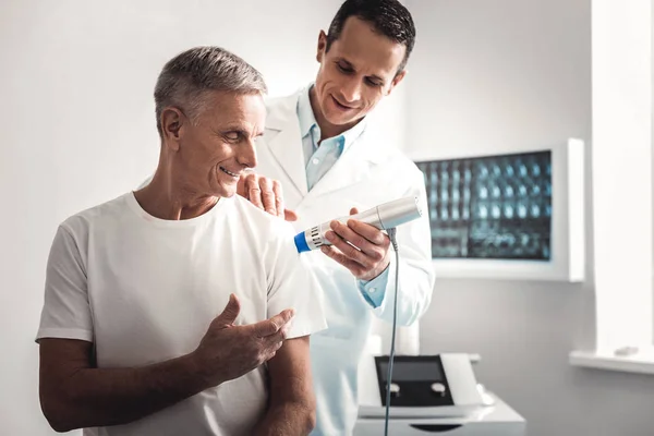 Smiling elderly man talking to doctor during checkup — Stock Photo, Image