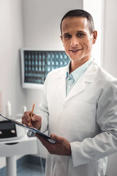 Quiroprático enrugado vestindo uniforme branco preparando registro de saúde — Fotografia de Stock
