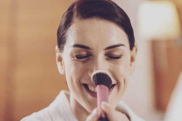 Cheerful model applying powder on her nose — Stock Photo, Image