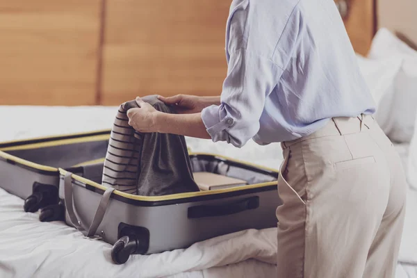 Крупный план оптимистичной женщины, складывающей чемодан — стоковое фото