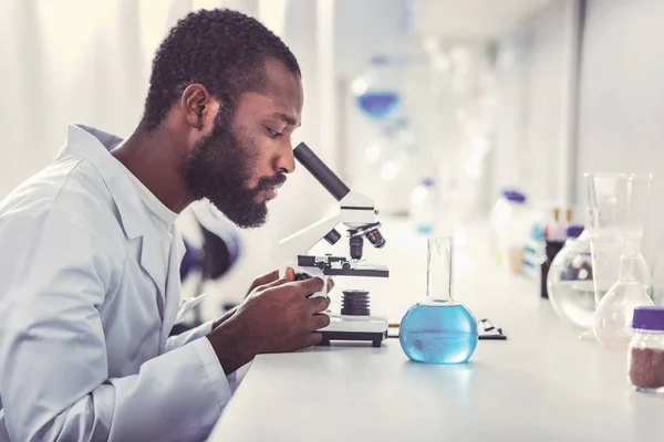 Jovem praticante de química olhando para o microscópio — Fotografia de Stock