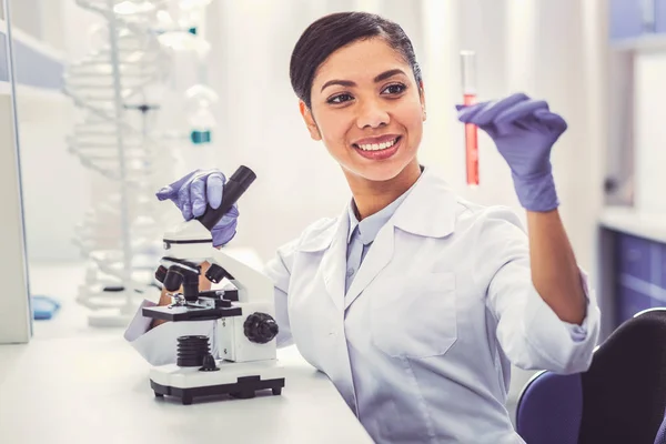 Encantadora química femenina sosteniendo el tubo de ensayo en la mano —  Fotos de Stock