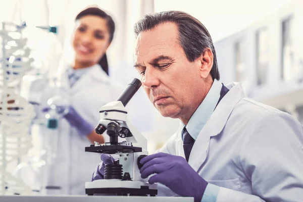 Old chemist wearing gloves working in laboratory — Stock Photo, Image