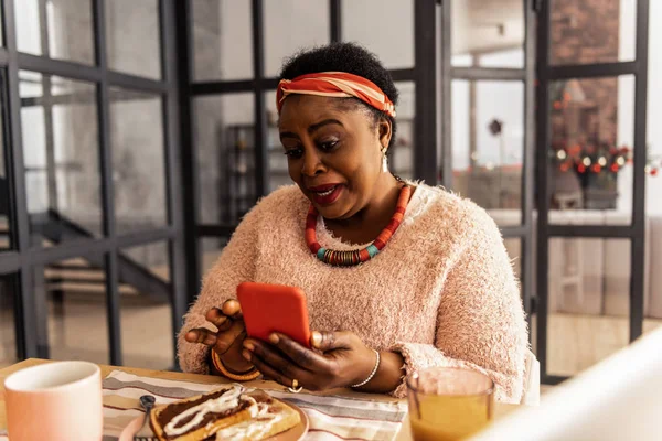 Mujer afroamericana encantada sosteniendo su teléfono inteligente — Foto de Stock