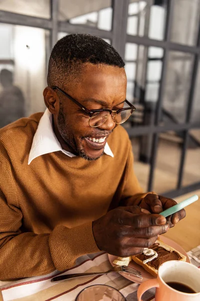 Feliz hombre alegre sentado con su teléfono inteligente — Foto de Stock