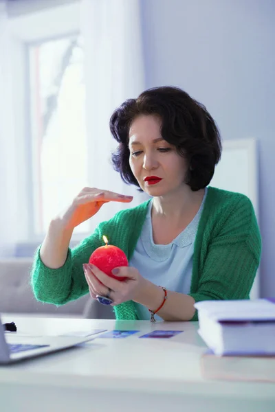 Serious nice woman looking at the candle light