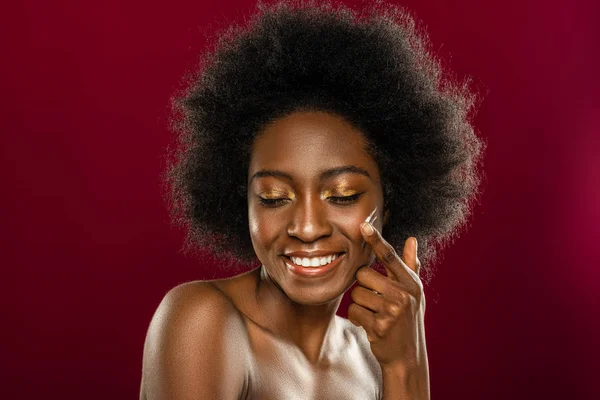 Rosto de uma jovem mulher alegre ao aplicar creme — Fotografia de Stock
