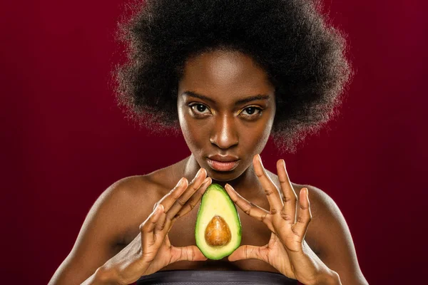 stock image Delicious fruit. Portrait of a serious beautiful woman standing with an avocado half