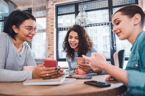 Bella donna positiva che mostra il suo smartphone ad un amico — Foto Stock