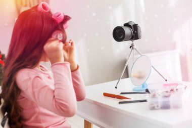 Küçük kız saç modeli yaparken fotoğraf makinesi ve küçük ayna önünde oturan