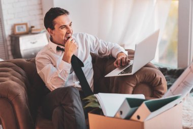 Zarif adam bir dizüstü bilgisayar ekranında bakarken esneme