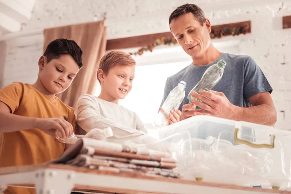 Усердный отец говорит со своими сыновьями о классификации отходов — стоковое фото