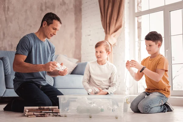 Diligent foster father telling his sons about trash recycling